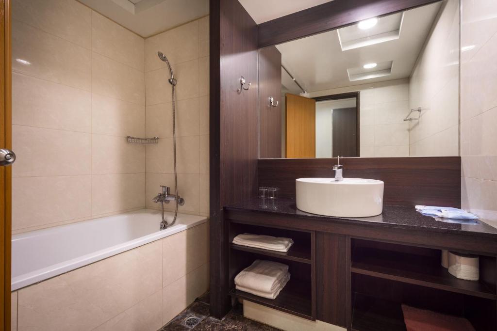 a bathroom with a sink and a tub and a mirror at Twinstar Hotel in Taichung