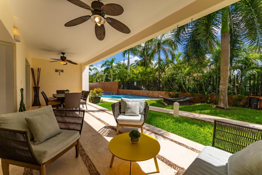a living room with a ceiling fan and a pool at Spacious Apartment with Terrace, Pool and Beach Access in Puerto Aventuras