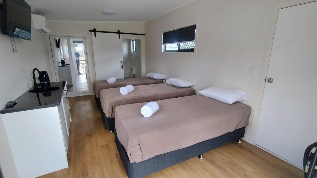 a room with two beds and a table and a kitchen at Guyra Club Cabins in Guyra