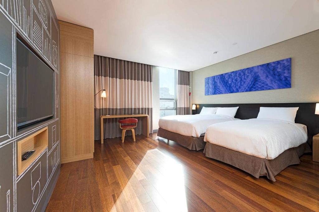 a hotel room with two beds and a flat screen tv at Central Seven Hotel by Kwon Busan Seomyeon in Busan
