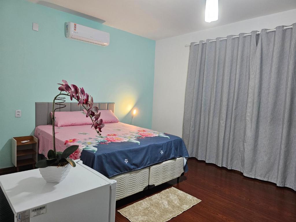 a bedroom with a bed and a table with a plant on it at Casa shanti living in Dourados