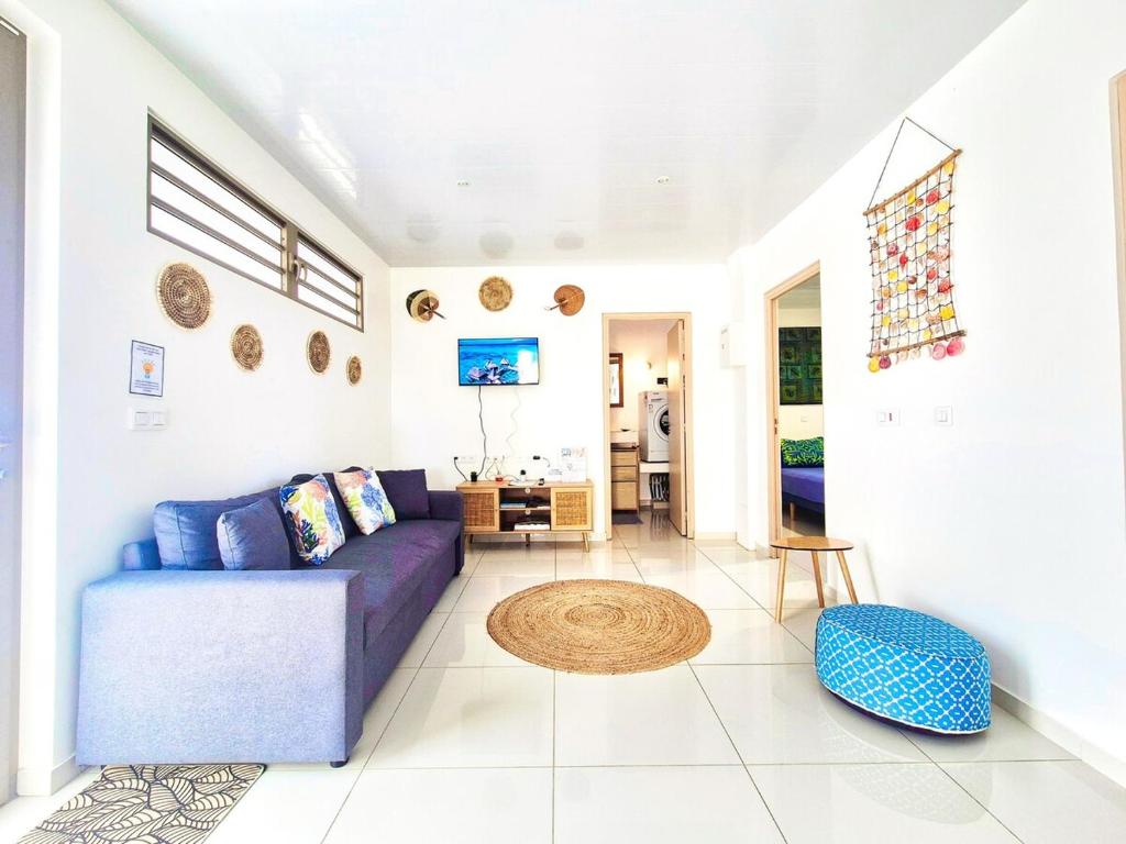 a living room with a purple couch and a table at Logement de charme, au soleil et proche de la mer in Moorea