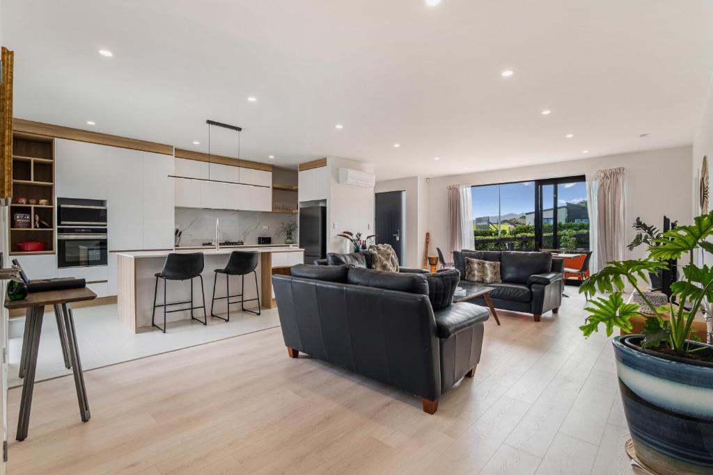 a living room with a couch and chairs and a kitchen at Puhinui House in Warkworth