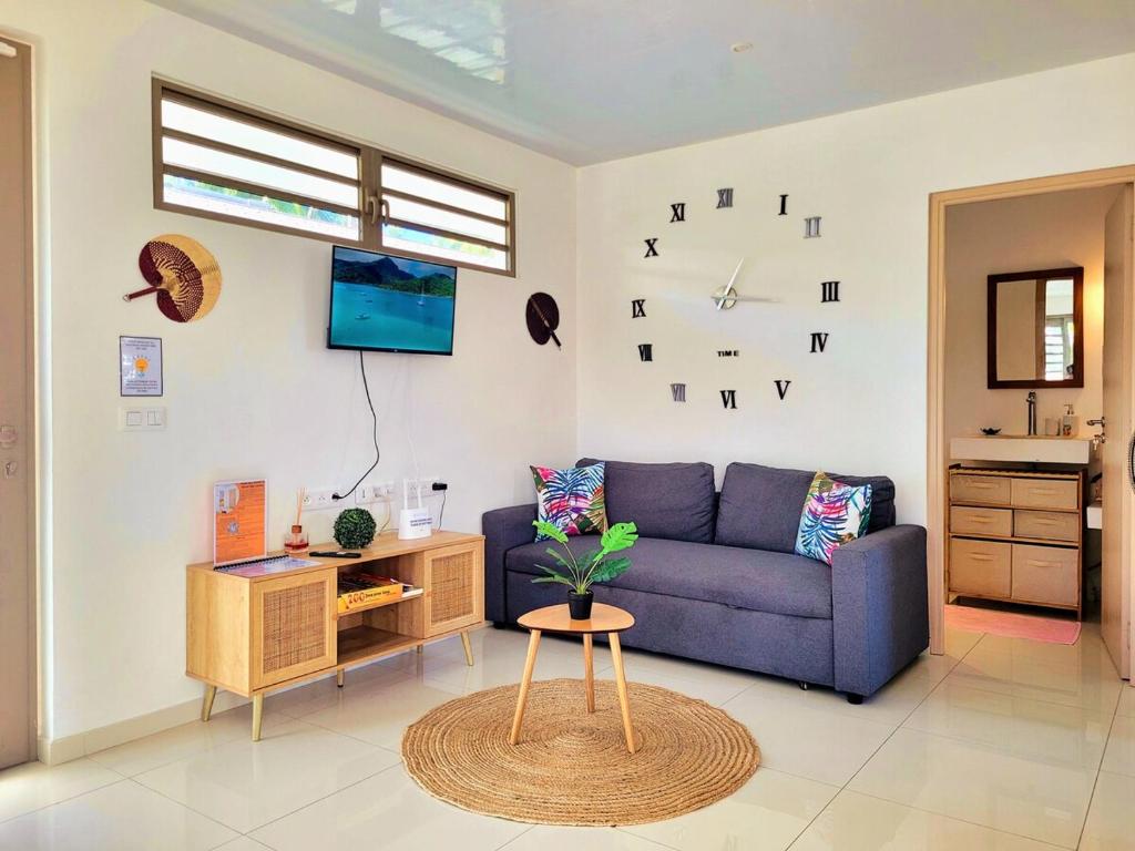 a living room with a blue couch and a table at Une pause au soleil et proche de la mer in Moorea