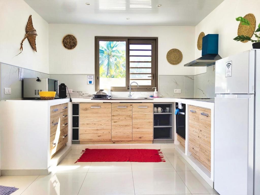 a kitchen with wooden cabinets and a red rug at Une pause au soleil et proche de la mer in Moorea