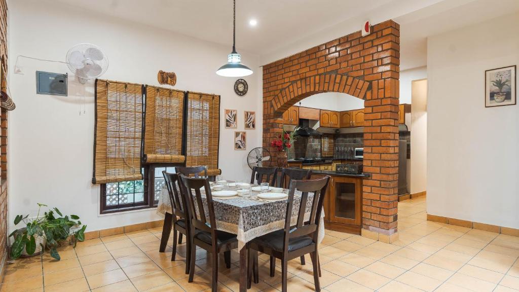 a dining room with a table and chairs and a brick wall at Goshen in Bengaluru