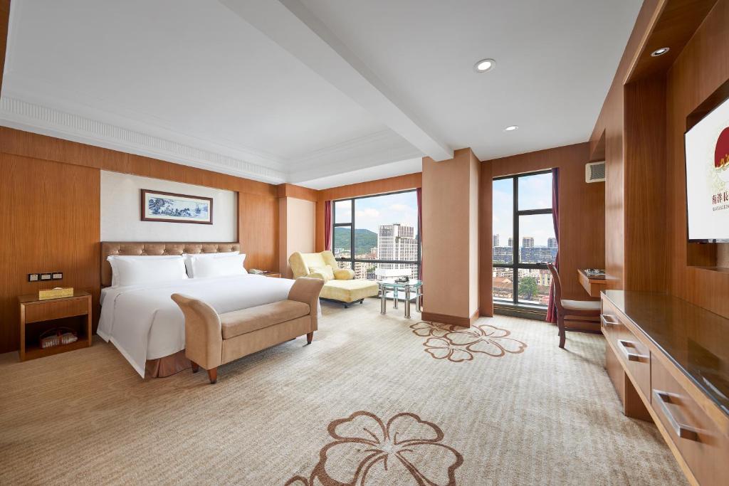 a hotel room with a bed and a couch and windows at Nanyang King's Gate Hotel--Free Shuttle Service to Canton Fair in Guangzhou