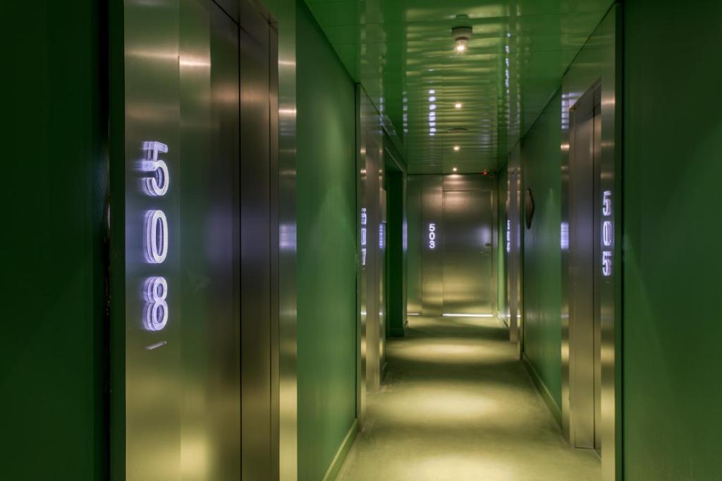 a hallway of a elevator with green walls and neon signs at Room Mate Oscar, Madrid in Madrid