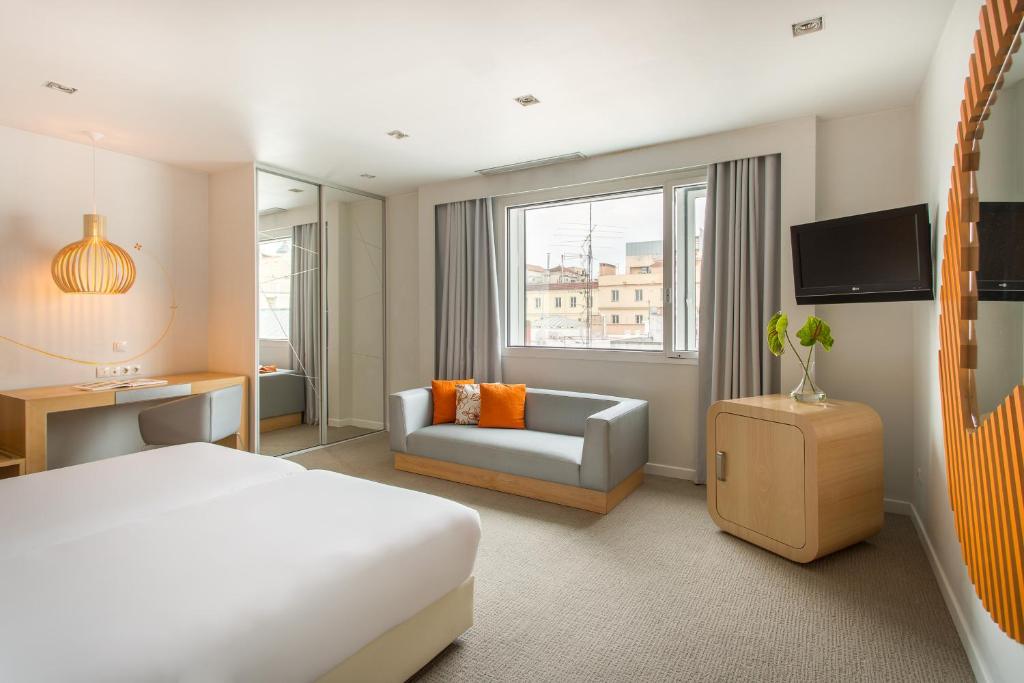 a hotel room with a bed and a couch and a tv at Room Mate Oscar, Madrid in Madrid