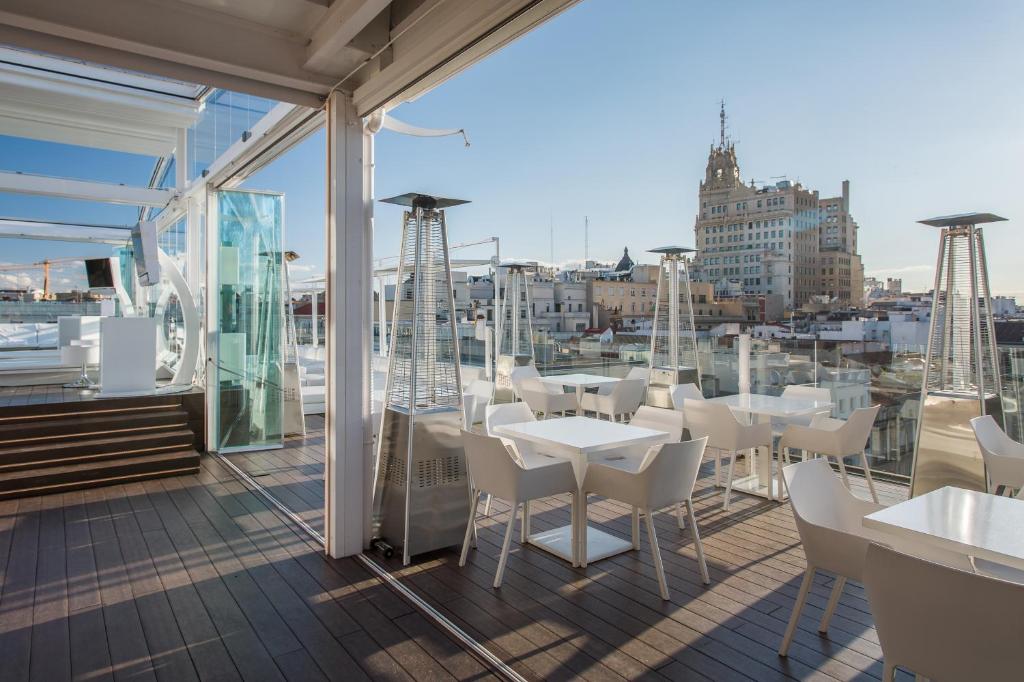 a balcony with white tables and chairs on a building at Room Mate Oscar, Madrid in Madrid