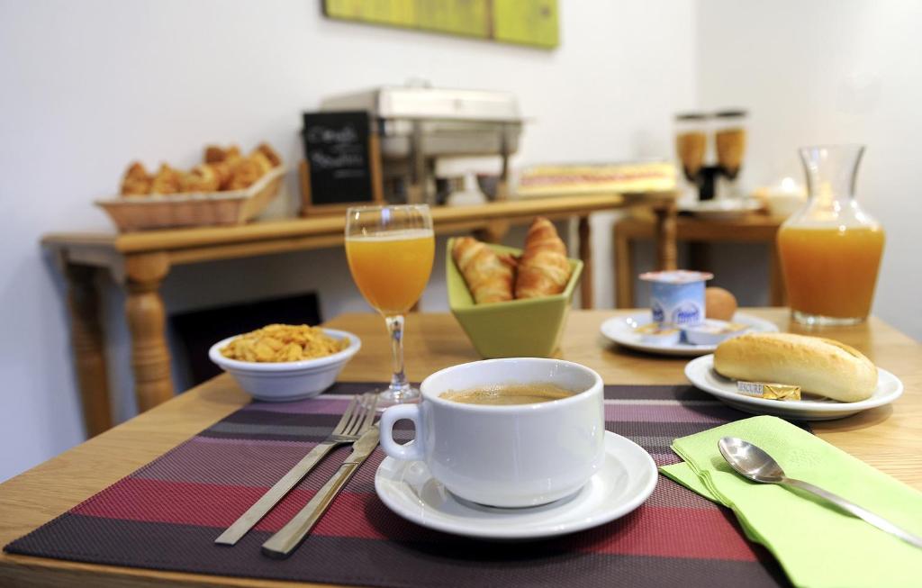 a table with a cup of coffee and a glass of orange juice at Odalys City Paris Levallois in Levallois-Perret