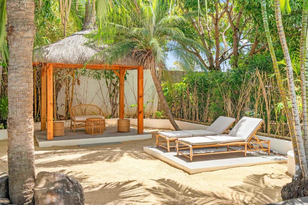 a patio with a gazebo and chairs and palm trees at Villa Kayou by Sealodge Mauritius in Tamarin