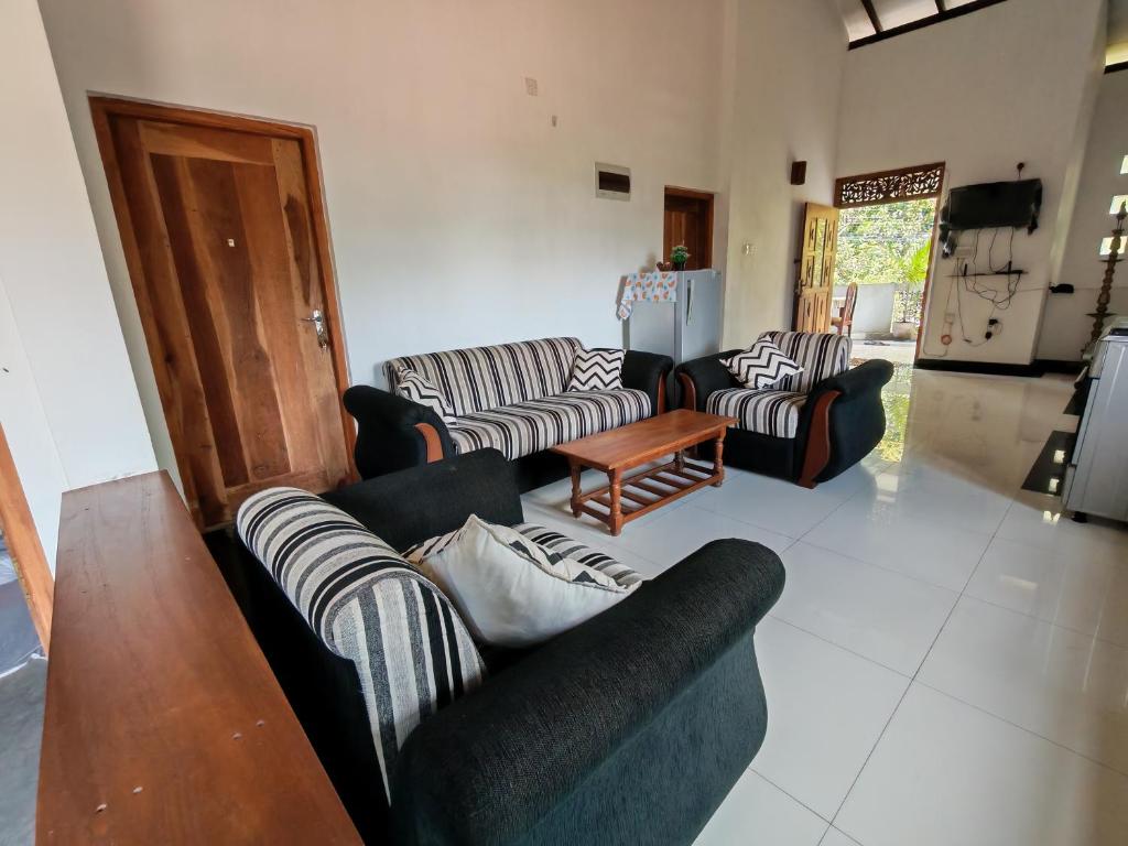 a living room with several couches and a table at Thaksilu Home in Mirissa