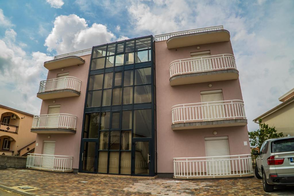a pink building with balconies on the side of it at Apartments Malina in Vir