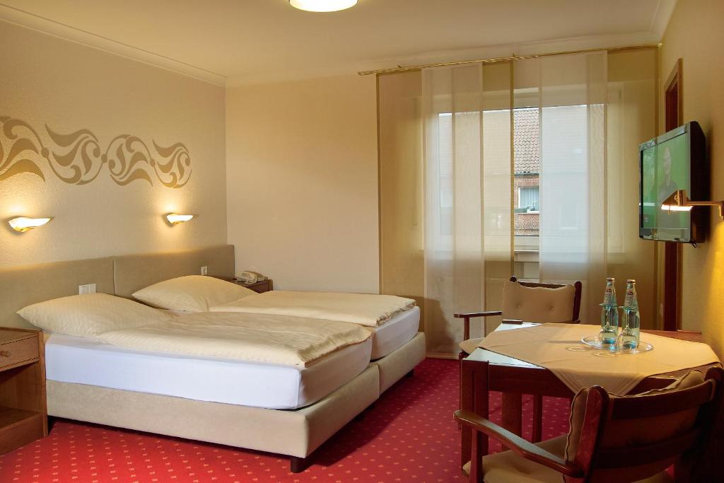 ein Hotelzimmer mit einem Bett und einem Tisch in der Unterkunft Hotel Restaurant Witte in Ahlen