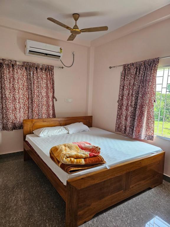 a bedroom with a bed with a fan and windows at Hotel Seven Heaven in mayapur