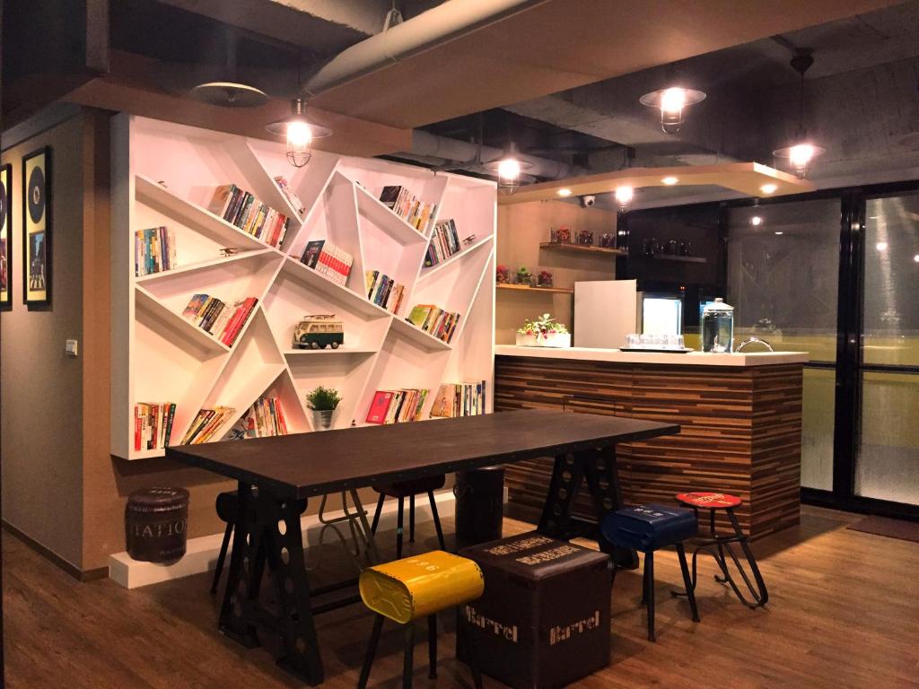 a table and chairs in a room with a book shelf at I Play Inn TP in Taipei