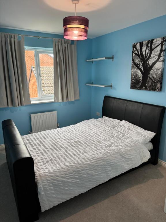 une chambre avec un lit avec un mur bleu dans l'établissement Cozy double room stay in Quedgeley, à Quedgeley
