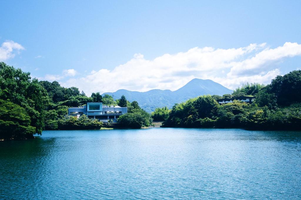 un lac avec une maison et des montagnes en arrière-plan dans l'établissement 時地人 - JIJIJIN Matsuyama, à Tobe