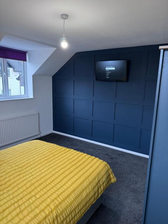 a bedroom with a yellow bed and a flat screen tv at Modern room in west hallam in Derby