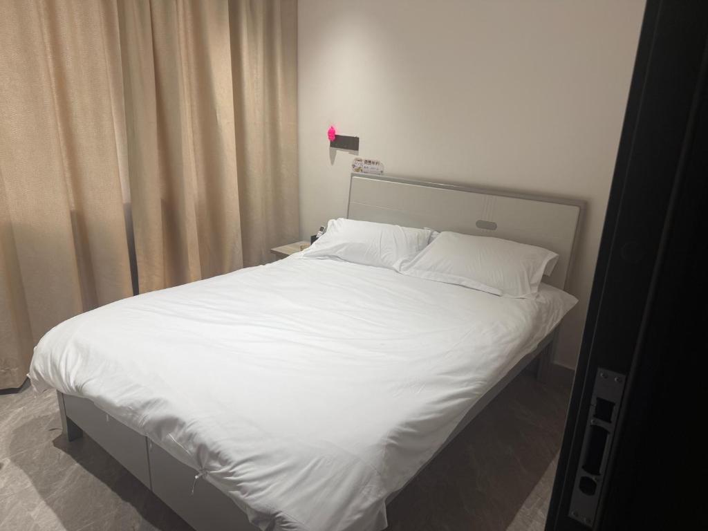 にあるRuifangju Homestay, Seaview Garden Communityの白いシーツと枕が付いた大きな白いベッド