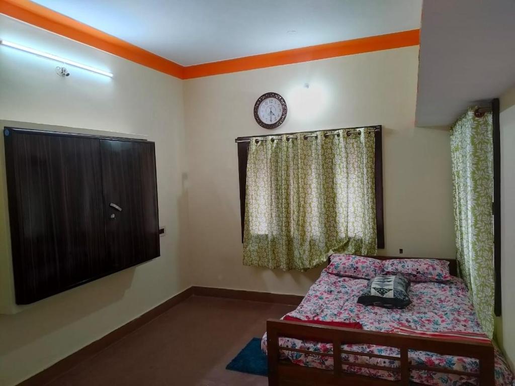 a bedroom with a bed and a clock on the wall at Roopa Studio in Mysore