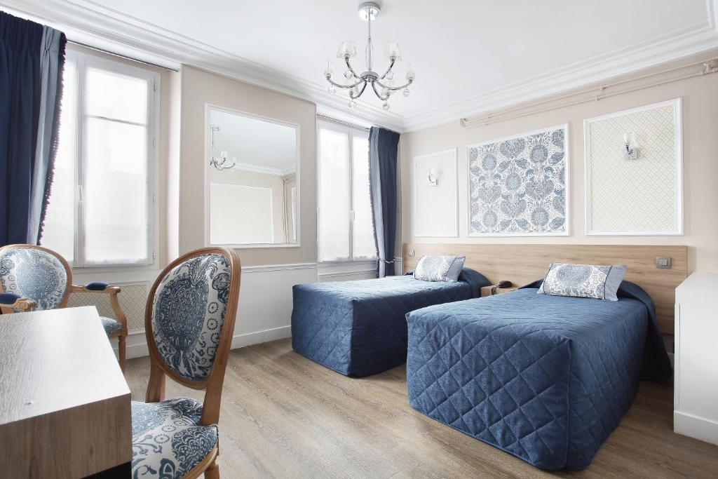 Cette chambre comprend deux lits, une table et des chaises. dans l'établissement Hotel Montpensier, à Paris