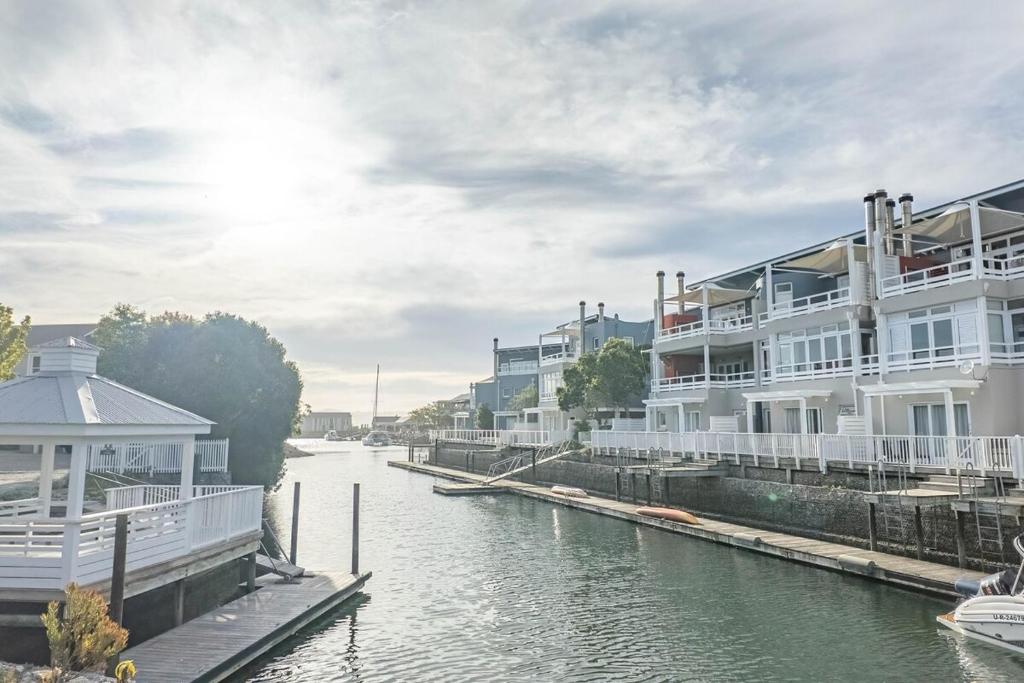 a body of water with buildings next to a river at The Anchor at Thesen Island in Knysna