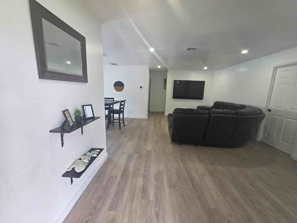 a living room with a black couch and a television at Delray Beach Sunshine - 5 minutes from beach! in Delray Beach