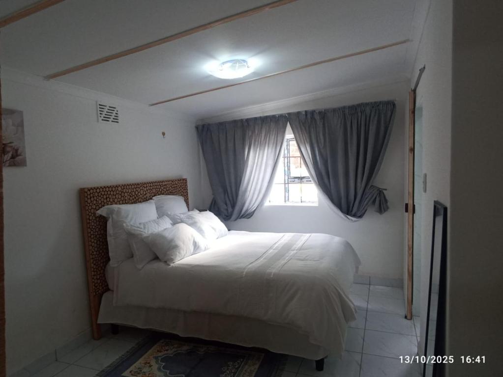 een slaapkamer met een groot bed met een raam bij Chez Matli in Tiervlei