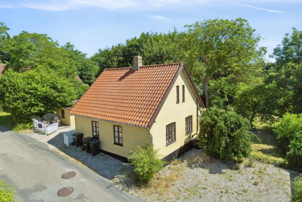 a small yellow house with an orange roof at Old Local House From 1904 With Natural Garden in Tranekær