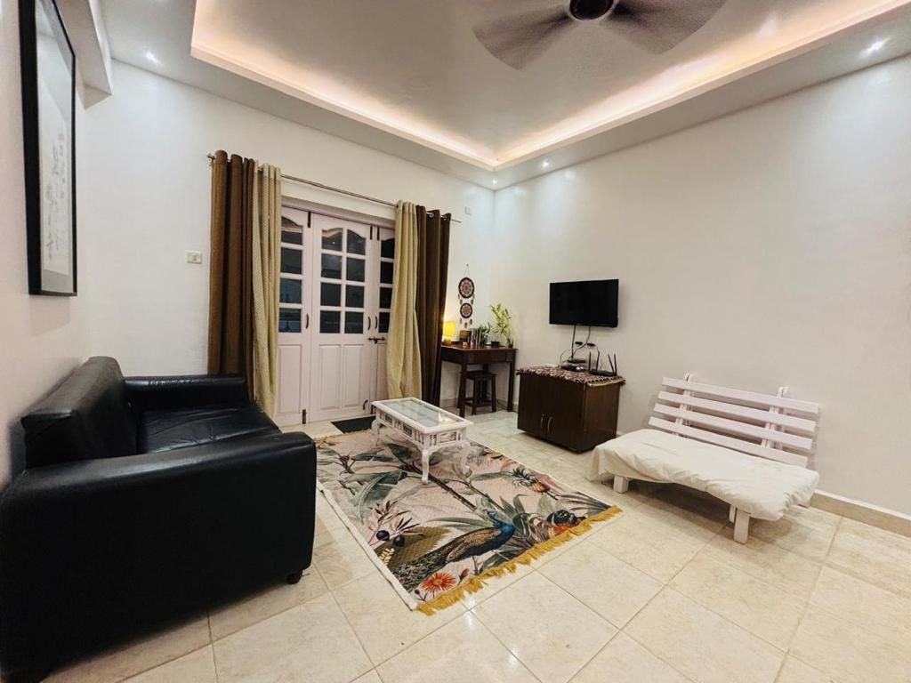 a living room with a black leather couch and a tv at 1bhk in Calangute North Goa nearby beach Sea Breeze Bay in Calangute