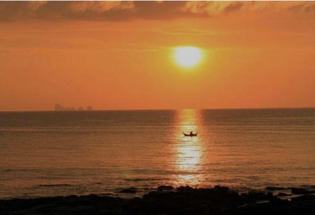 - un bateau dans l'océan au coucher du soleil dans l'établissement Happy Beach Hostel, à Ko Lanta Yai