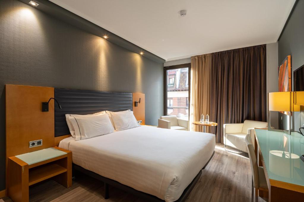 a hotel room with a large bed and a desk at Eurostars Indautxu in Bilbao