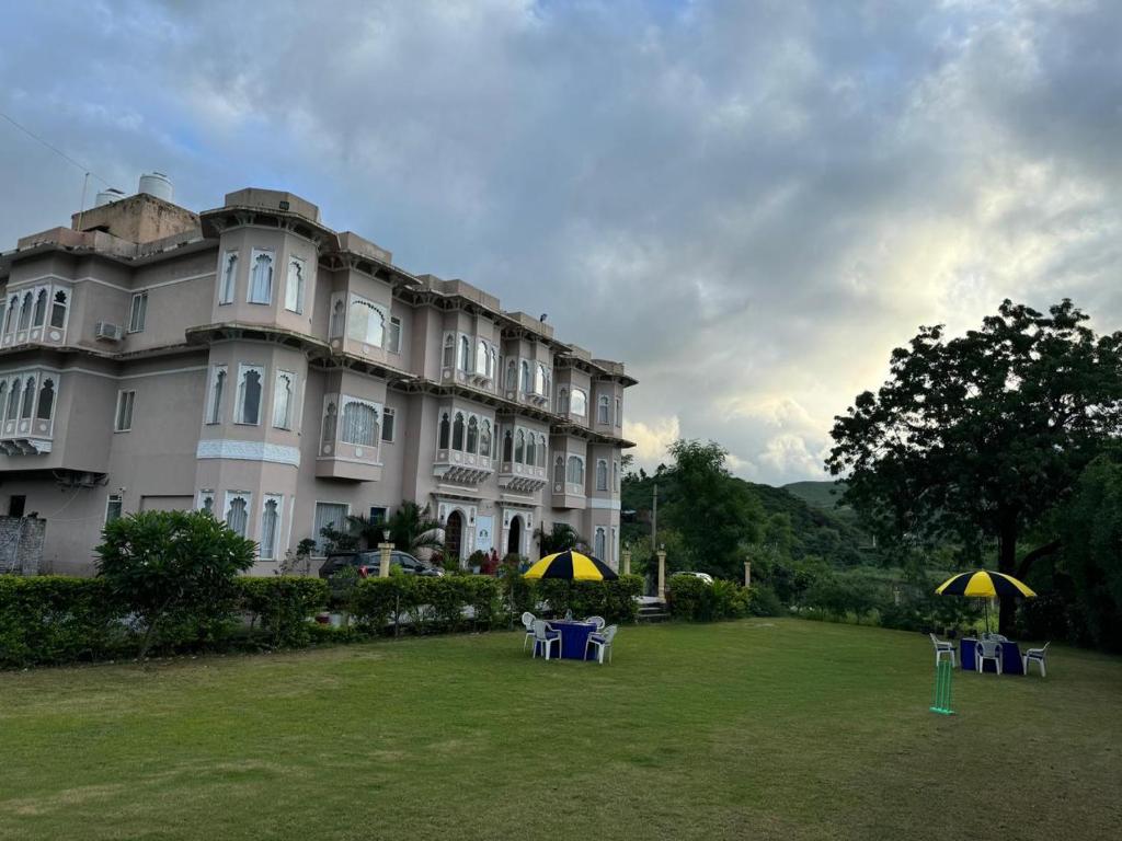 a large building with two tables and umbrellas in front of it at Royal Haveli With Swimming Pool in Nāi