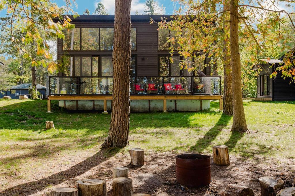 a house with a deck in the yard with trees at 3-bedroom Lakefront Villa #5 in Lakefield