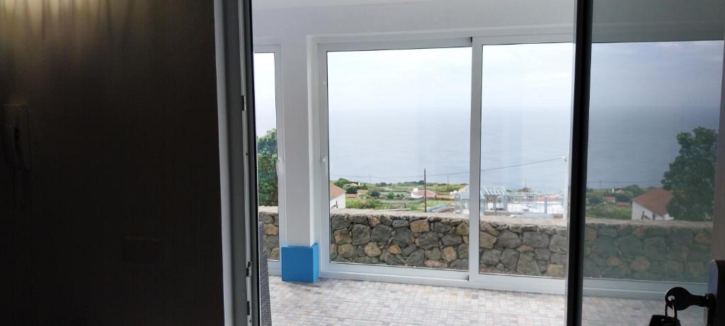 a room with a window with a view of a rock wall at Stunning ocean view with 3 islands in front of you in Serreta