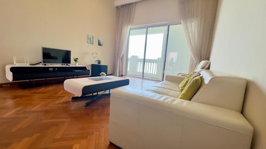 a living room with a white couch and a tv at Straits Quay Seaview in Tanjung Bungah