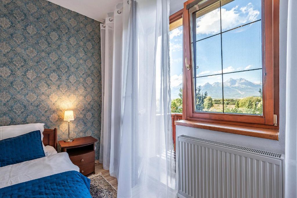 een slaapkamer met een bed en een raam bij Apartmán KaTry in Veľká Lomnica