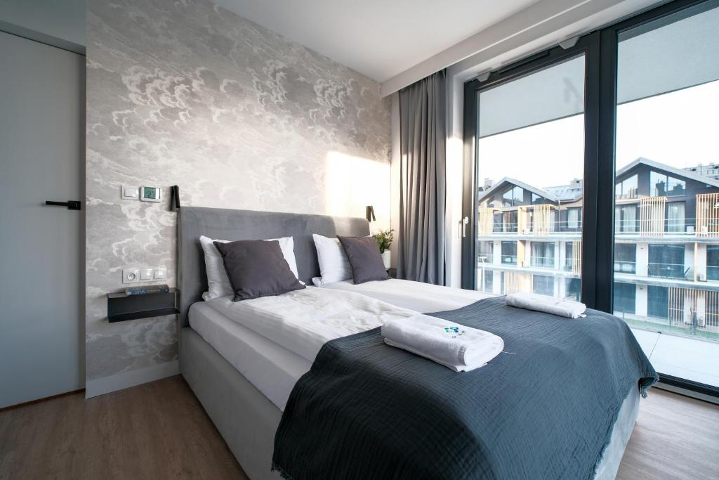 ein Schlafzimmer mit einem großen Bett und einem großen Fenster in der Unterkunft Laguna Beskidów Resort - Apartamenty Royal in Zarzecze