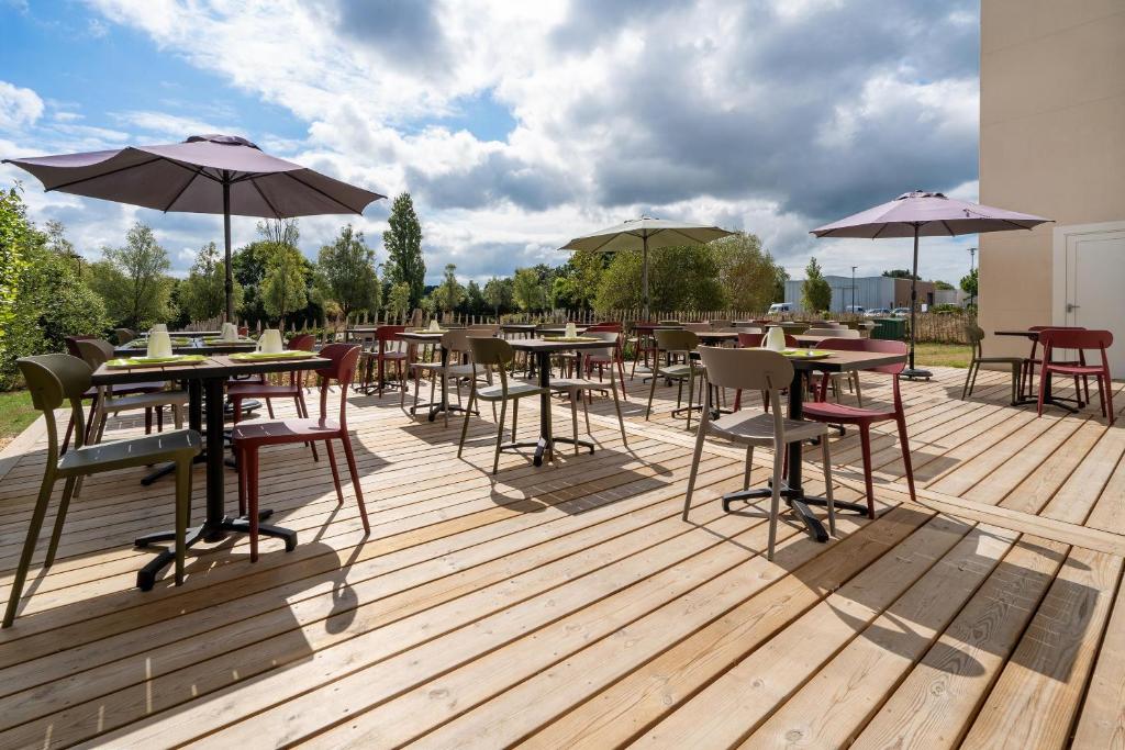 a wooden deck with tables and chairs and umbrellas at Sure Hotel By Best Western Guerande in Guérande