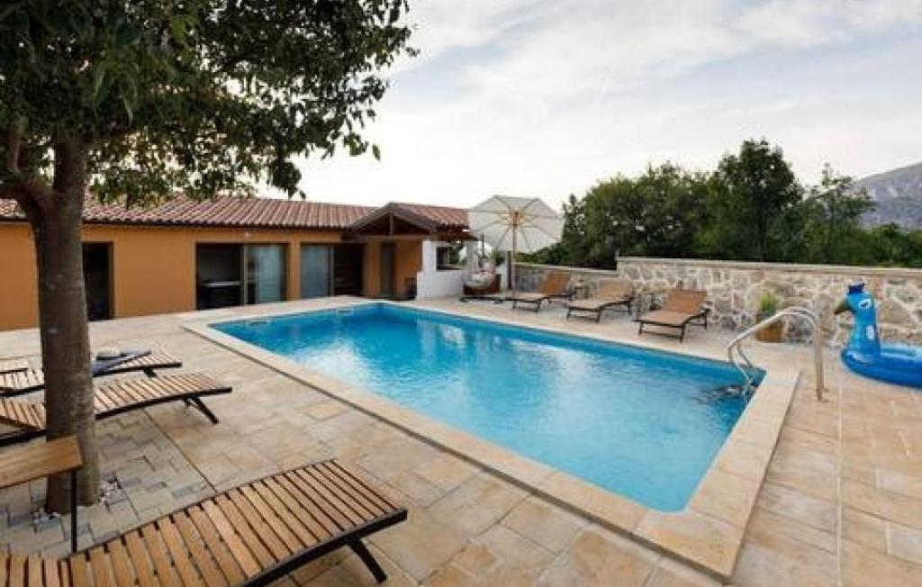 a swimming pool with chairs and a house at Holiday home Lisnjak by Villas Guide in Trbounje