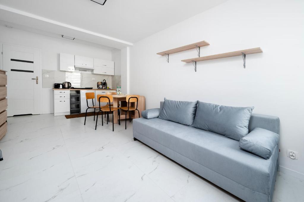 a living room with a blue couch and a kitchen at Łódź Urban Serenity Studio #10 by BookingHost in Łódź