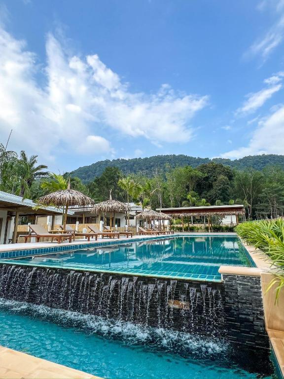 a swimming pool with a waterfall in front of a resort at The Palm Villa in Ban Ai Dao
