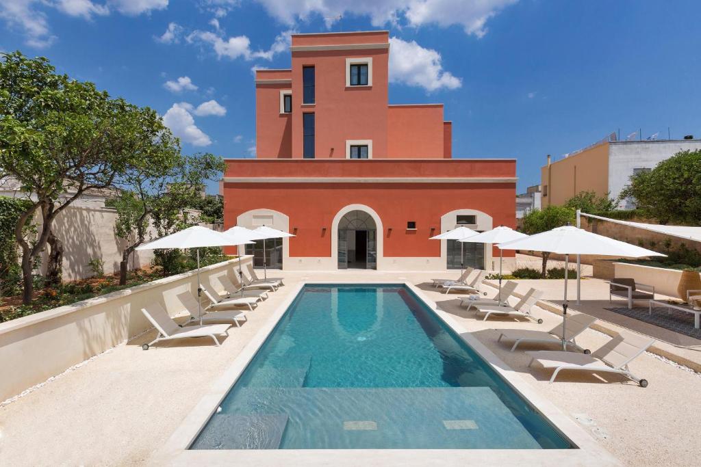 a swimming pool with lounge chairs and a building at Palazzo Fasti in Casarano