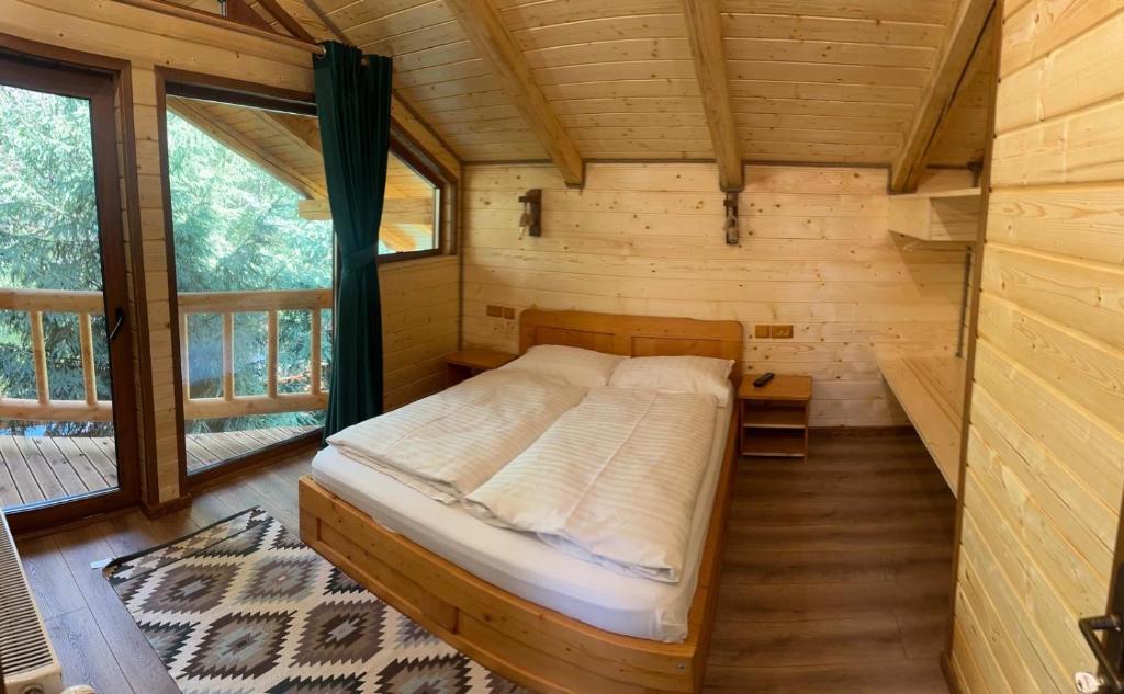 a bedroom in a log cabin with a bed in it at Pensiunea Plaiul Bucovinei in Şarul Dornei