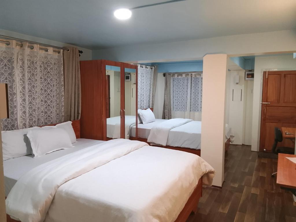 a hotel room with two beds with white sheets at Spring Grove B&B in Jowai