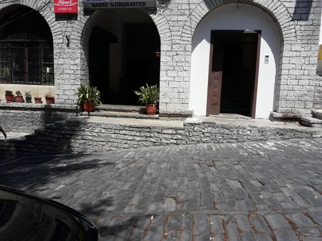 a building with arches and a brick courtyard with potted plants at Tina's Apartment in Gjirokast&euml;r
