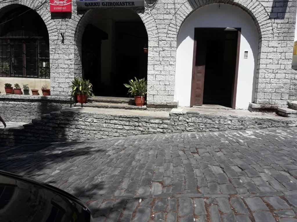 a building with arches and a brick courtyard with potted plants at Tina's Apartment in Gjirokastër