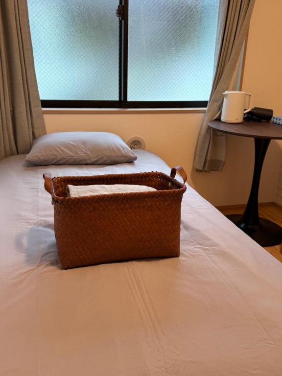 a basket sitting on top of a bed with a window at 新宿区の新築木造アパート-駅から徒歩5分 in Tokyo